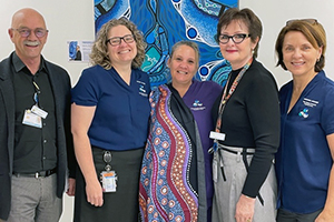 An Aboriginal graduate midwife stands between four other nursing and midfwifery staff